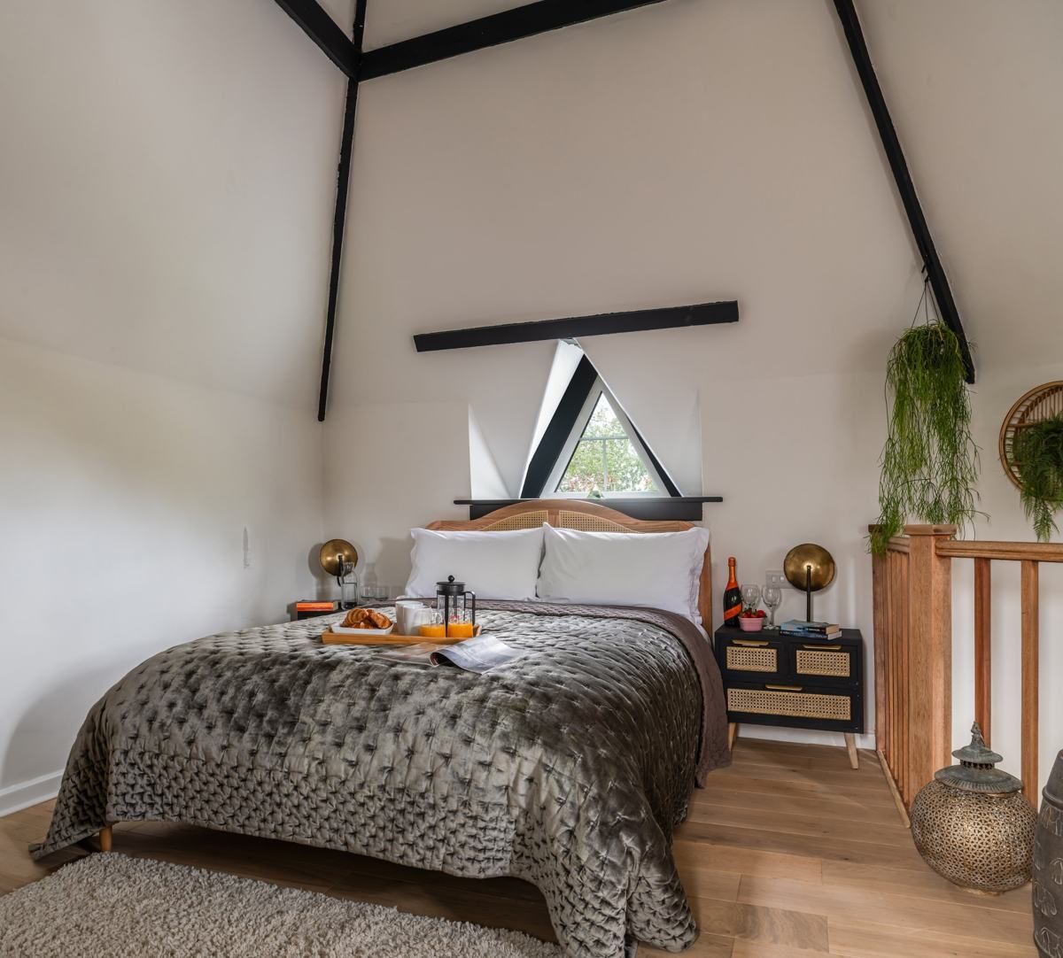 Double bed under the triangular window in the turret bedroom, Fairy Cottage at Lea Hall